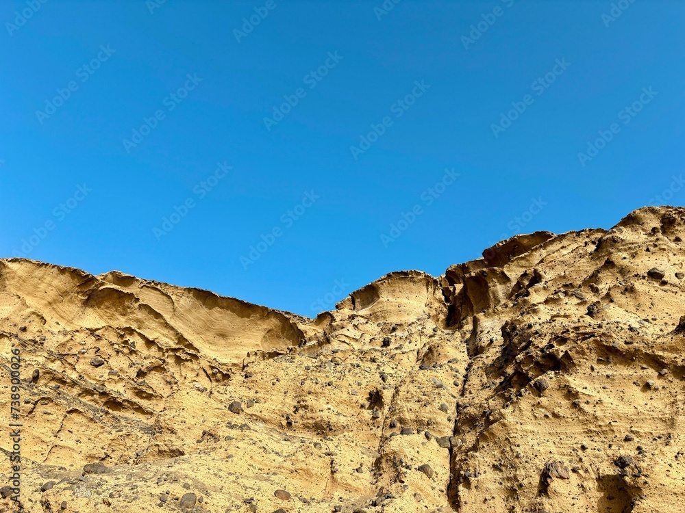 Volcanic cliff on the blue sky background in Pelada Beach, El Medano, Canary Islands, Spain