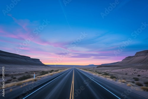 A lone highway heading straight into a breathtaking sunrise, with the desert sky painted in pastel shades of pink and blue. The lighting is gentle and diffuse, casting a warm glow over the desert. © SardarMuhammad