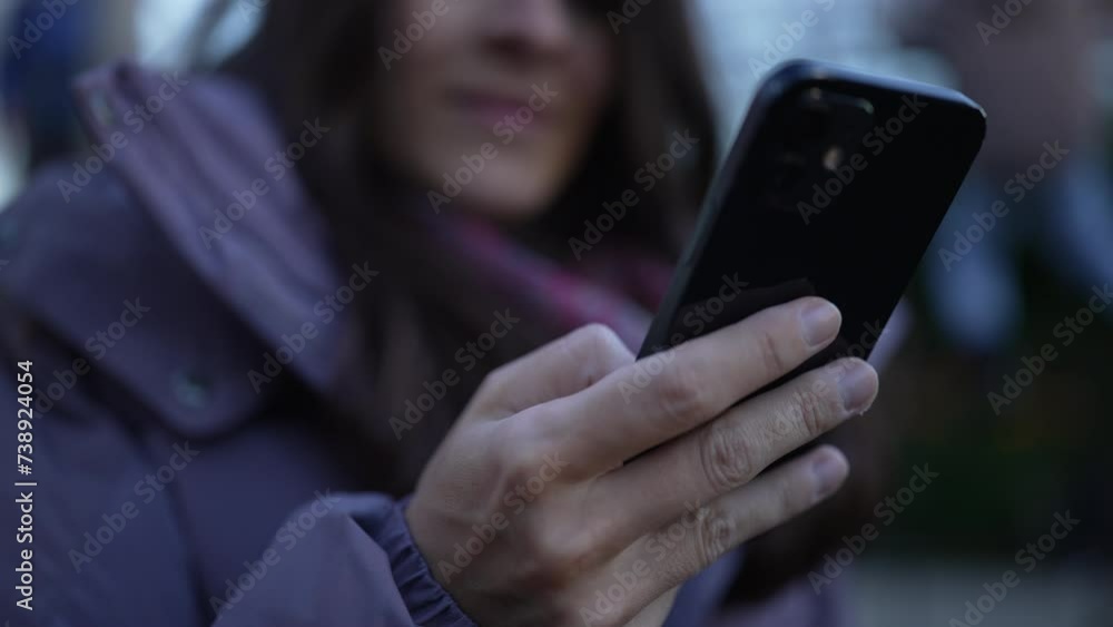 Woman holding phone, close-up hand while rack focus to face with smile, 30s female person engaged with modern technology Woman holding phone, close-up hand while rack focus to face with smile, 30s female person engaged with modern technology