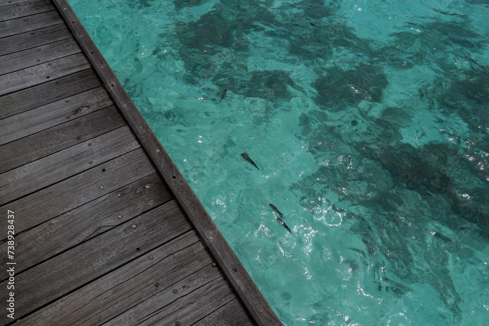 View of turquoise ocean water from a wooden deck in the Maldives