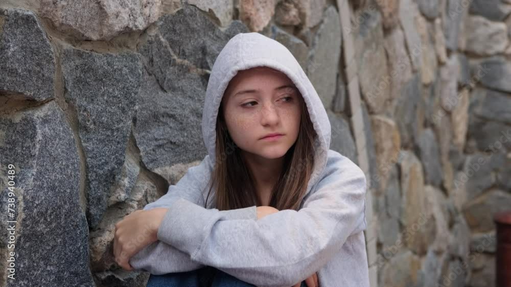 Sad depressed teenage girl in a hood sleeps alone on the street, feeling angry and lonely. Growing crisis and anxiety. Concept of self-acceptance and self-analysis. Homeless Sad depressed teenage girl in a hood sleeps alone on the street, feeling angry and lonely. Growing crisis and anxiety. Concept of self-acceptance and self-analysis. Homeless