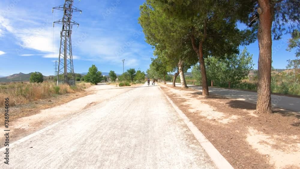 French Way of Saint James - a family cycling a gravel road next to La Grajera recreational park and reservoir in Logrono, La Rioja, Spain French Way of Saint James - a family cycling a gravel road next to La Grajera recreational park and reservoir in Logrono, La Rioja, Spain