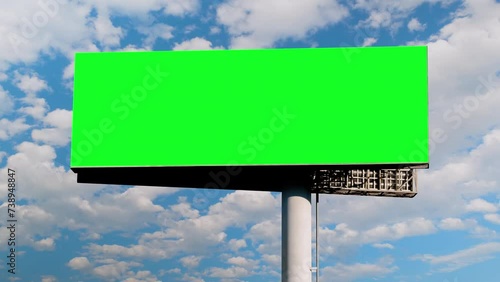 Timelapse: blank green billboard or large display and moving white clouds in the blue sky. Green screen, template, time lapse, copy space, mock up and outdoor advertising concept photo