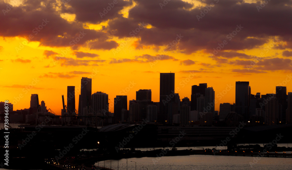 Panorama sunset silhouette of Miami downtown from South Beach with skyscrapers and cruise terminal against the orange sky of the setting sun 