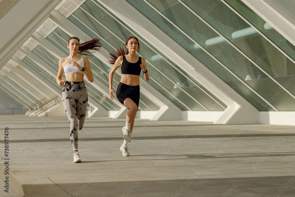 Two athletic women in sportswear is jogging around the city in early morning. Reaching the goal Two athletic women in sportswear is jogging around the city in early morning. Reaching the goal