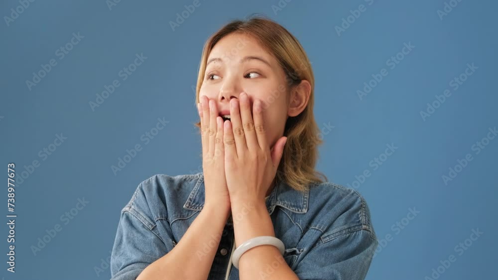 Surprised woman covering her mouth with her hands isolated on blue background Surprised woman covering her mouth with her hands isolated on blue background