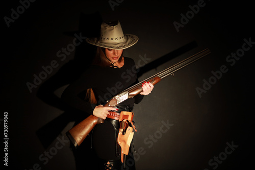 Foto Beautiful young woman with shotgun and old revolver low key portrait