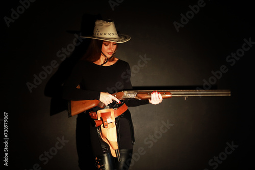 Beautiful young woman with shotgun and old revolver low key portrait