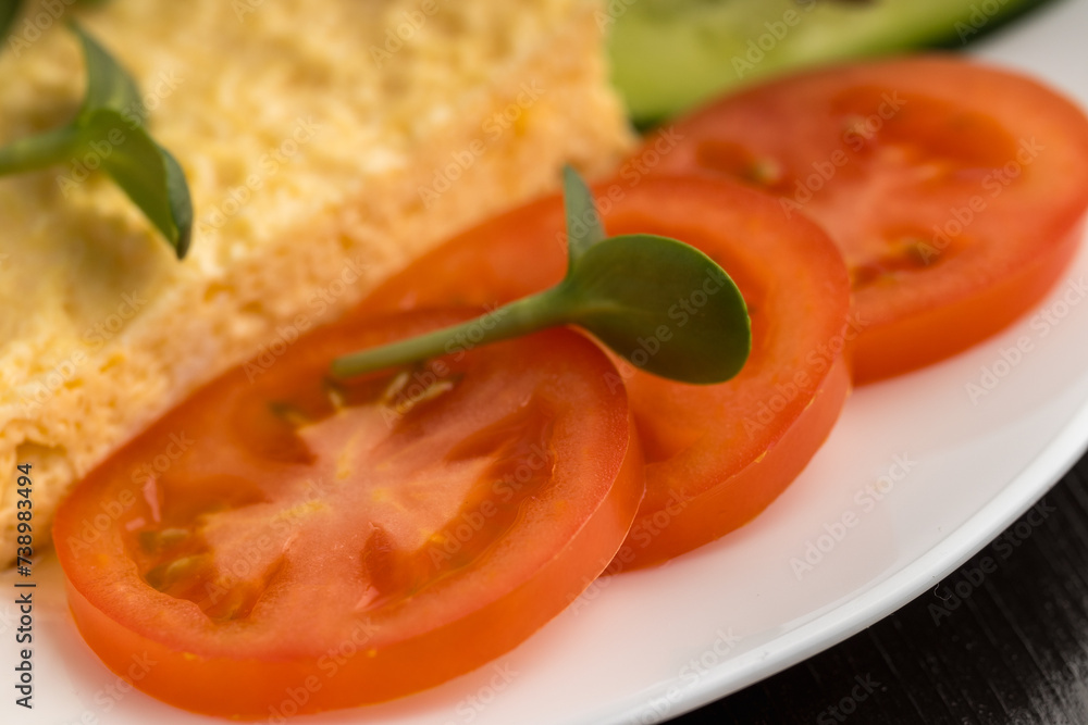 Close-up of an omelette with tomatoes and a microgreen on a white plate Close-up of an omelette with tomatoes and a microgreen on a white plate