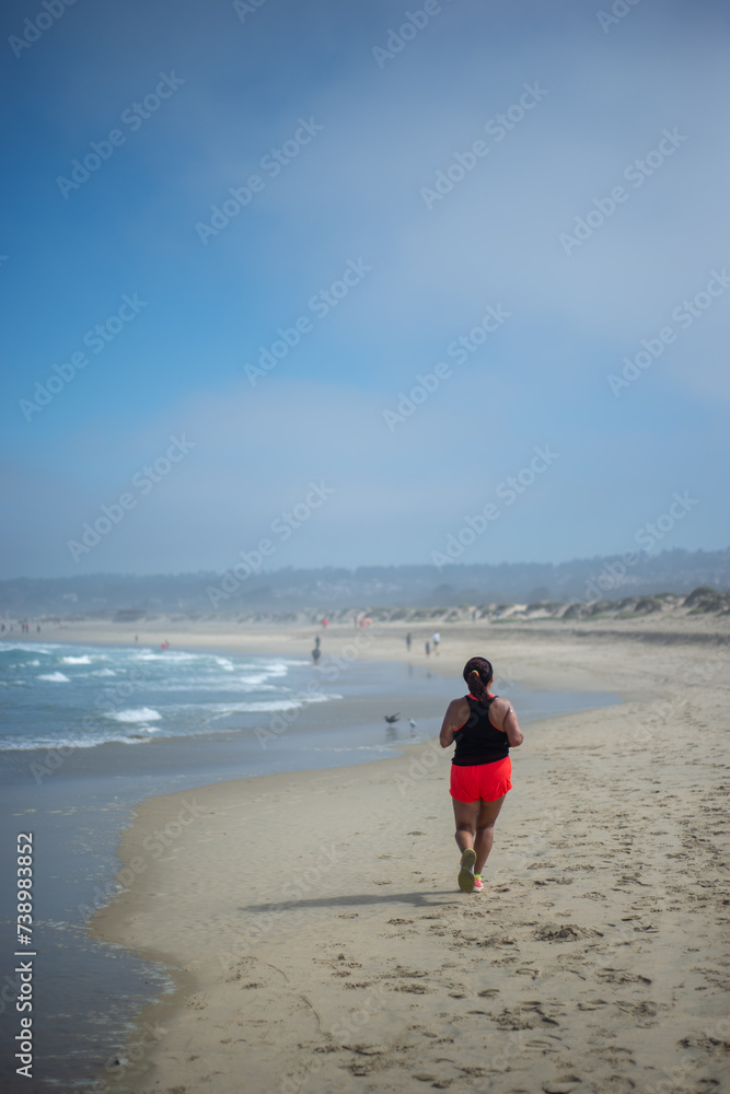 a middle age woman running on the sand of El Tabo beach, Valparaiso, Chile