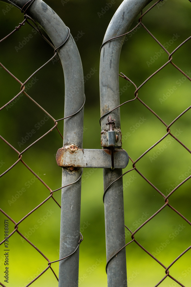Rusty chain link fence up close with green plant bokeh background Rusty chain link fence up close with green plant bokeh background