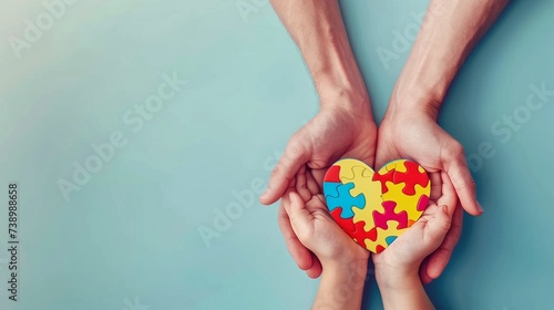 World autism awareness day concept, adult and child hands holding puzzle heart on light blue background, copy space