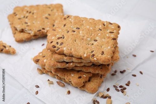 Stack of cereal crackers with flax and sesame seeds on white tiled table, closeup