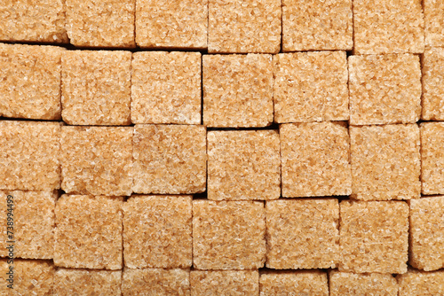 Brown sugar cubes as background, top view