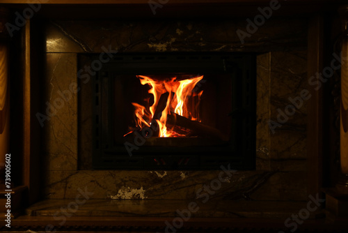 Fireplace with burning wood in darkness indoors