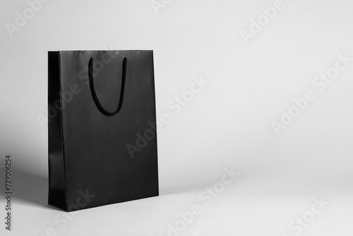 One black paper shopping bag on grey background. Space for text
