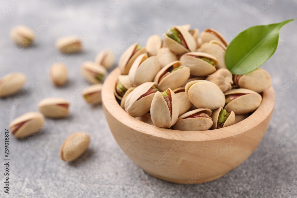 Delicious pistachios in bowl on grey textured table Delicious pistachios in bowl on grey textured table