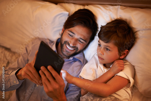 Bedroom, father and son with tablet, night and family with ebook and connection with social media. Dad, house and boy with technology and bedtime story with lights and bonding together with hobby photo