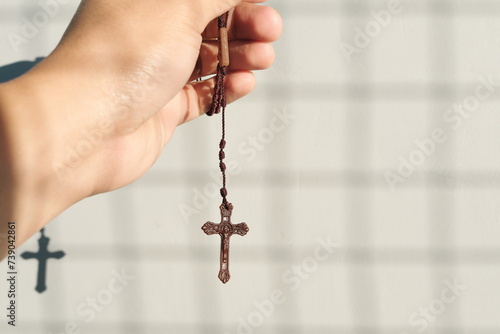 Male hand holding holy rosary with shadow. Christianity, faith and praying concept.