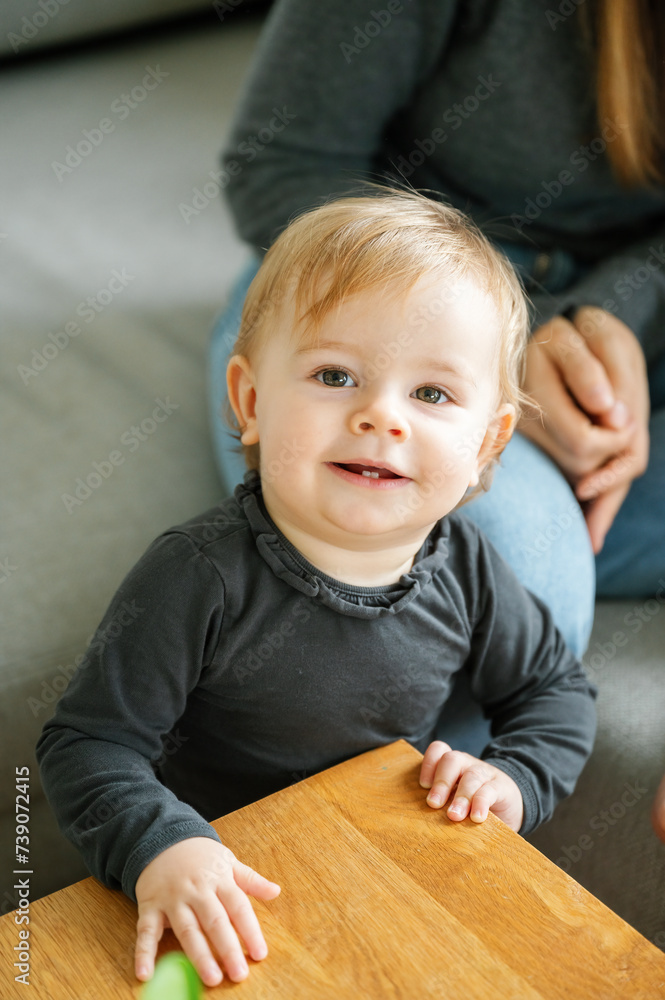 Toddler girl standing at wooden table and smiling Toddler girl standing at wooden table and smiling