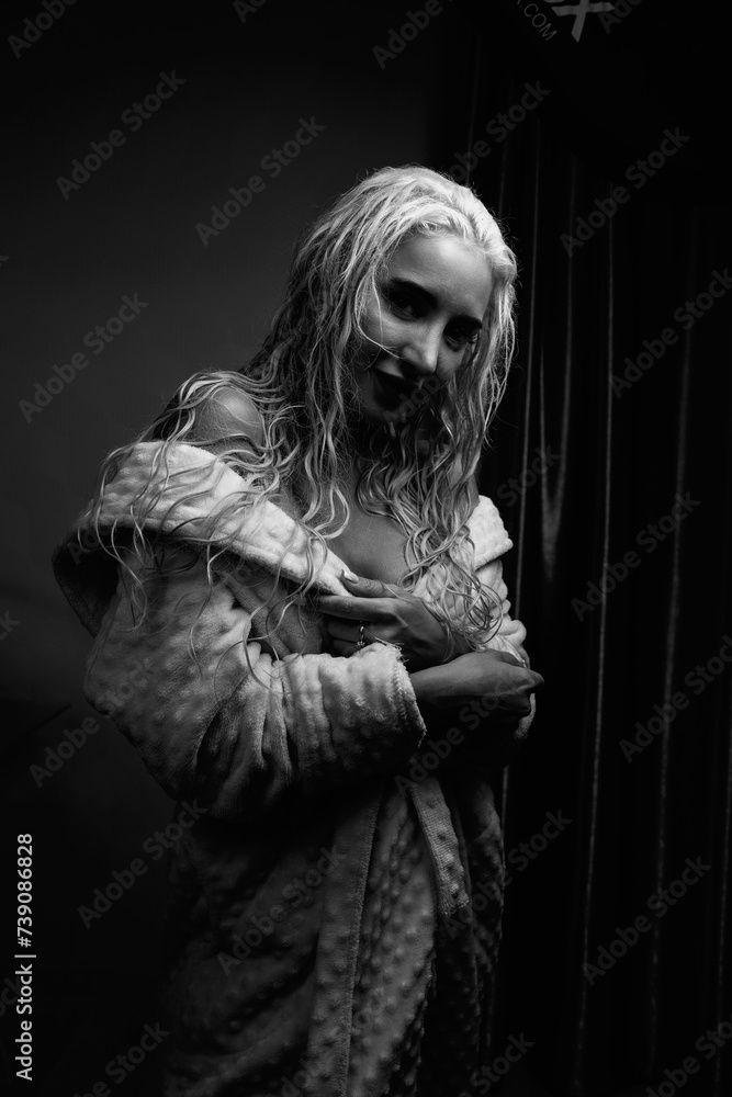 Portrait of a young girl with blond hair in a dressing gown in a low key. Portrait of a young girl with blond hair in a dressing gown in a low key.
