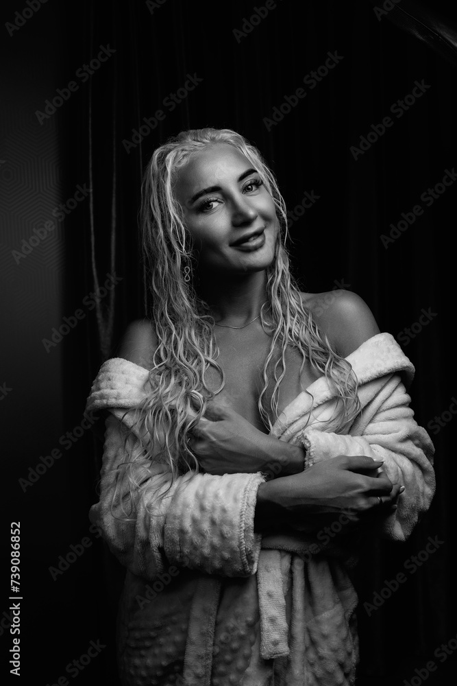 Portrait of a young girl with blond hair in a dressing gown in a low key.