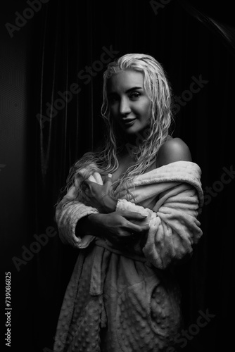 Portrait of a young girl with blond hair in a dressing gown in a low key. © shymar27