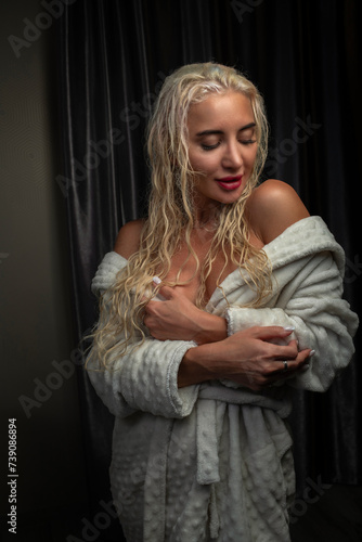 Portrait of a young girl with blond hair in a dressing gown in a low key.