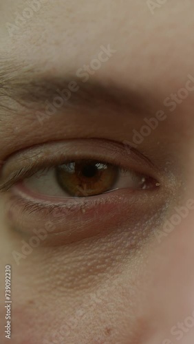 Vertical video. Extreme close-up shot of handsome man with green eyes, looking at camera
