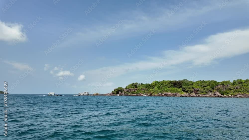Serene tropical island with lush greenery, surrounded by blue ocean waters with tour boats in the distance, under a sunny sky with light clouds ideal for vacation and travel concepts Serene tropical island with lush greenery, surrounded by blue ocean waters with tour boats in the distance, under a sunny sky with light clouds ideal for vacation and travel concepts