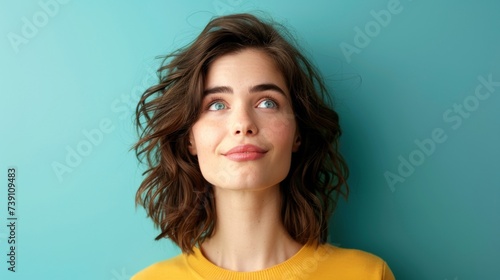 Dreamy young woman with short hair against blue backdrop. © Iona