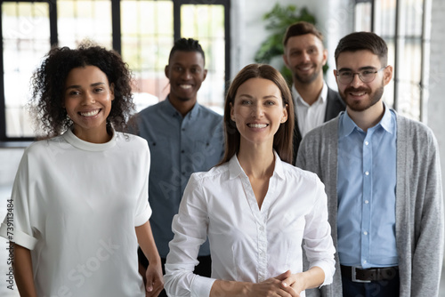 Happy successful coworkers and start-up coach. Group portrait of aspiring young professionals at work, smiling and looking at camera. Friendly multiracial company staff together in modern workspace photo