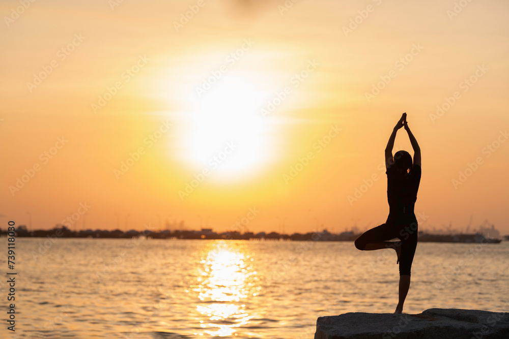 Yoga silhouette woman on the ocean during amazing sunset. Fitness and healthy lifestyle.