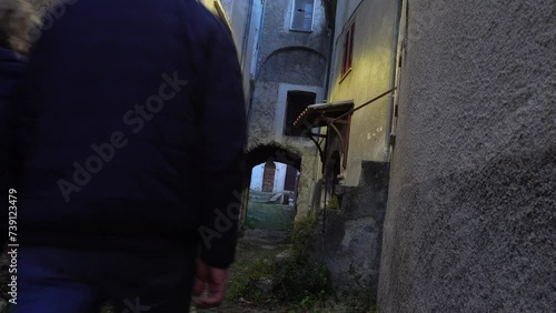 Secinaro, Italy A tourist couple walk in an old alley past abandoned houses photo