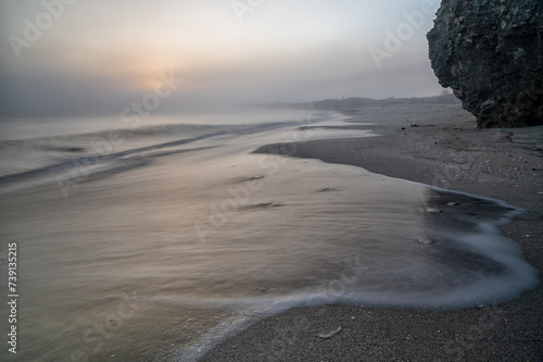 Alba sul mare, con riflesso del sole sull'acqua e sulla sabbia, cielo con la nebbia. photo