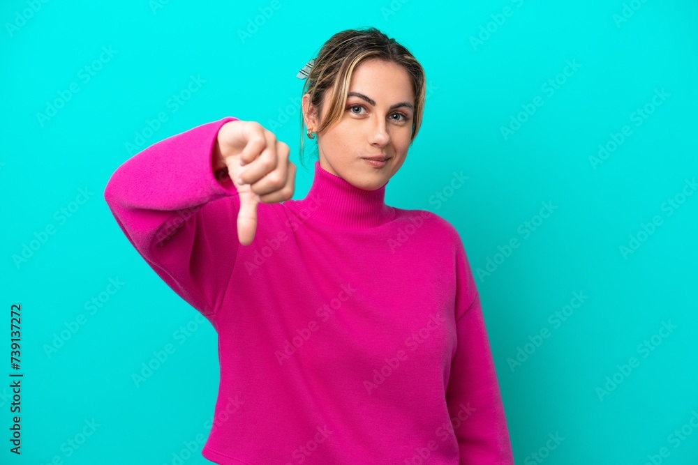 Fototapeta premium Young caucasian woman isolated on blue background showing thumb down with negative expression