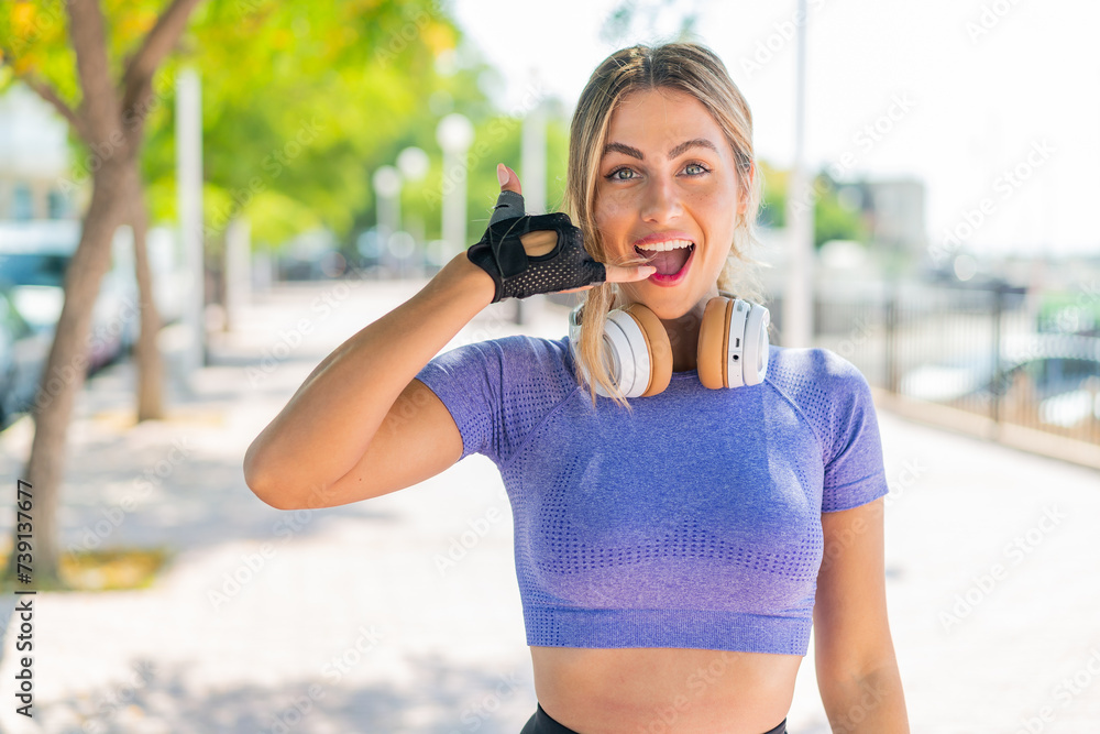 Young pretty sport woman at outdoors making phone gesture. Call me back sign Young pretty sport woman at outdoors making phone gesture. Call me back sign