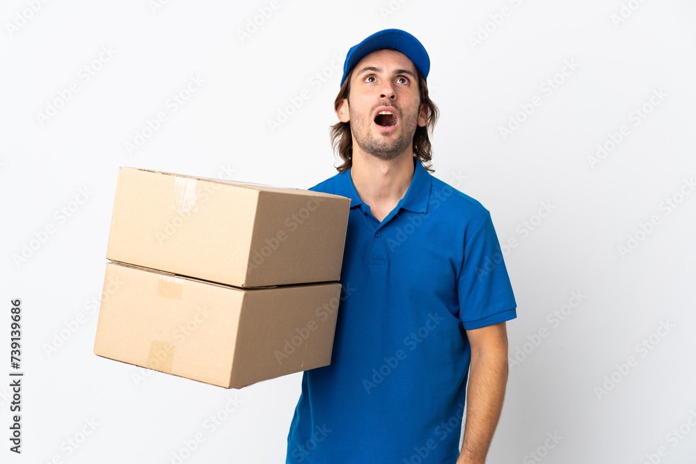 Delivery man isolated on white background looking up and with surprised expression Delivery man isolated on white background looking up and with surprised expression