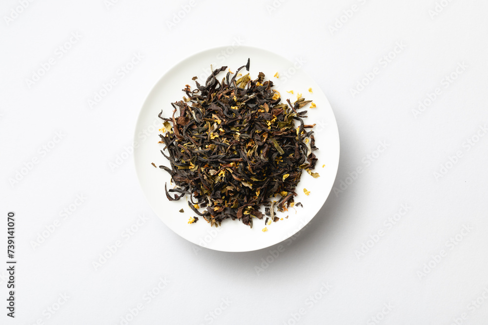 Osmanthus black tea on white porcelain saucer. Osmanthus black tea sample. black tea leaves Osmanthus black tea on white porcelain saucer. Osmanthus black tea sample. black tea leaves