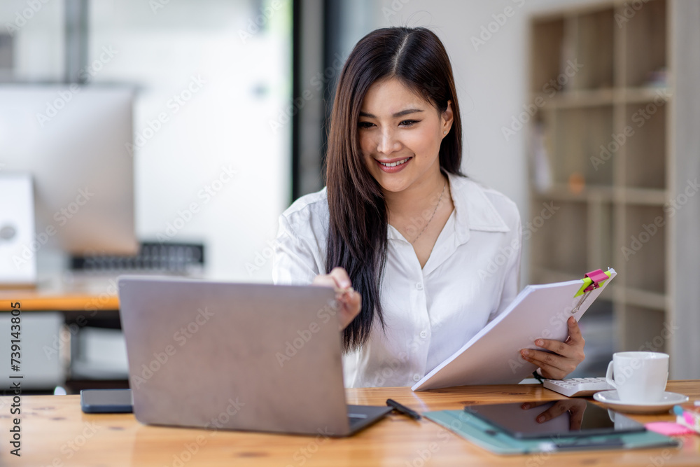 Asian Businesswoman Using laptop computer and working at office with calculator document on desk, doing planning analyzing the financial report, business plan investment, finance analysis concept.
Asian Businesswoman Using laptop computer and working at office with calculator document on desk, doing planning analyzing the financial report, business plan investment, finance analysis concept.