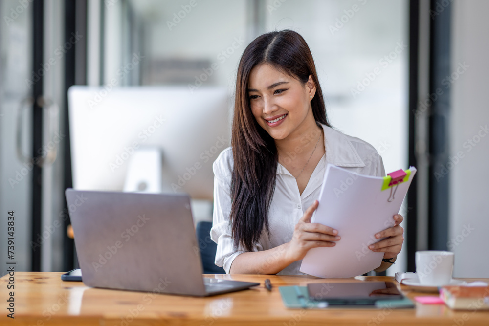 Asian Businesswoman Using laptop computer and working at office with calculator document on desk, doing planning analyzing the financial report, business plan investment, finance analysis concept.
Asian Businesswoman Using laptop computer and working at office with calculator document on desk, doing planning analyzing the financial report, business plan investment, finance analysis concept.