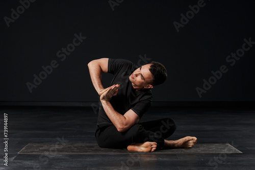 The attractive male yogi, donning sleek black garments, exudes a sense of serenity and strength as he deeply connects with his inner self through a series of intricate poses.