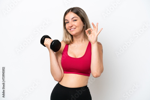 Young sport Rumanian woman making weightlifting isolated on white background showing ok sign with fingers © luismolinero