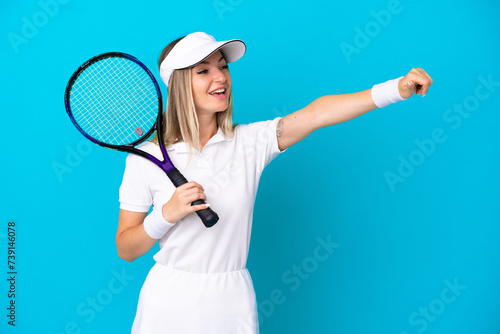 Young tennis player Romanian woman isolated on blue background giving a thumbs up gesture © luismolinero