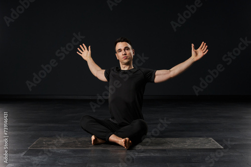  In his striking black attire, the alluring man practices yoga with a mesmerizing fluidity, each posture a work of art in motion on his mat.