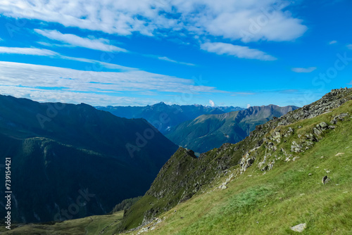 Lush green alpine meadow with panoramic view of majestic mountain peaks of High Tauern National Park  Carinthia  Austria. Wanderlust in Austrian Alps. Idyllic high altitude hiking trails in summer