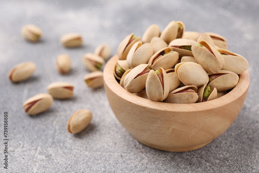 Delicious pistachios in bowl on grey textured table Delicious pistachios in bowl on grey textured table