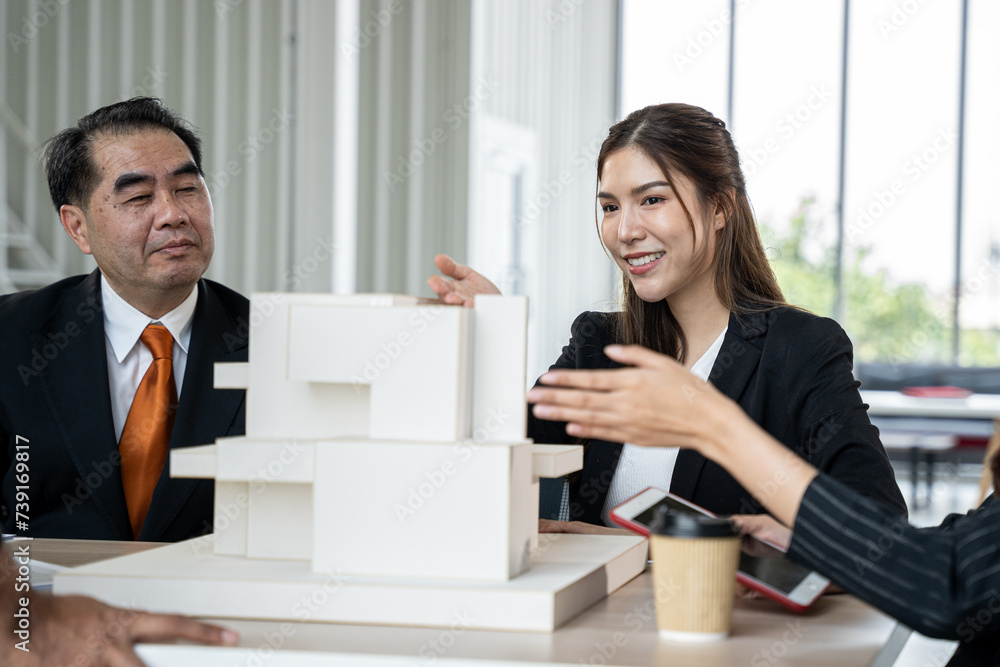 Asian business woman presenting building model with team in office. They dissing about building model design together. Asian business woman presenting building model with team in office. They dissing about building model design together.