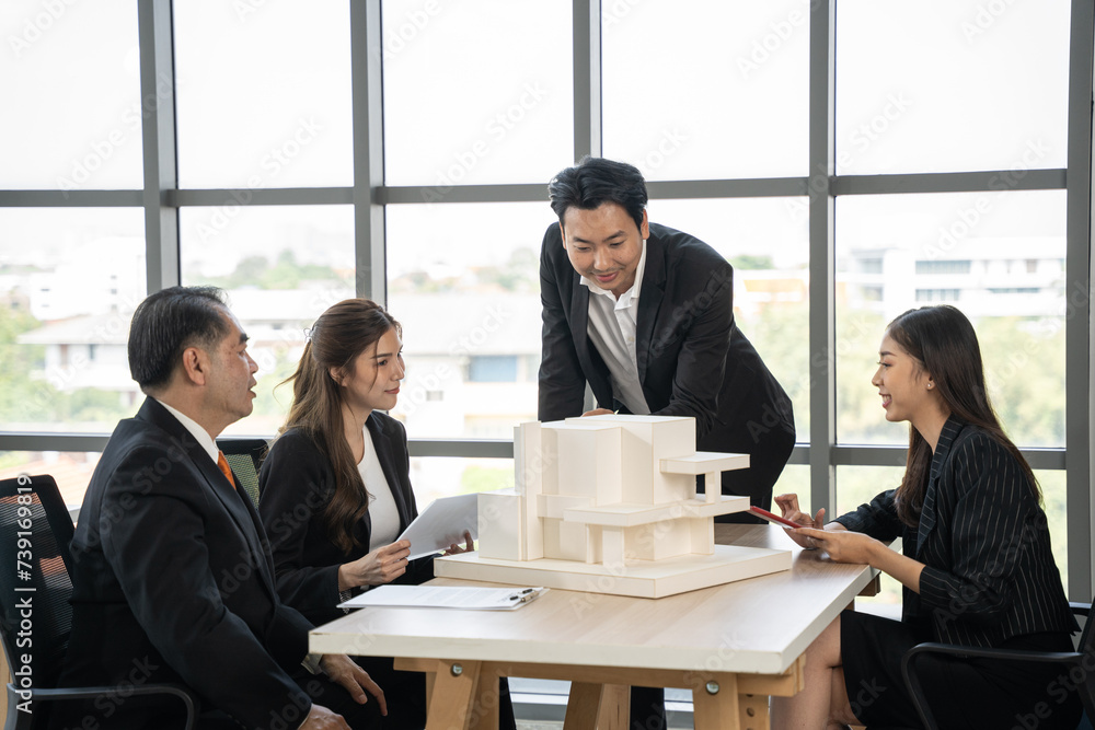 Fototapeta premium Asian businessman talking with team in meeting room. They dissing about building model and design together.