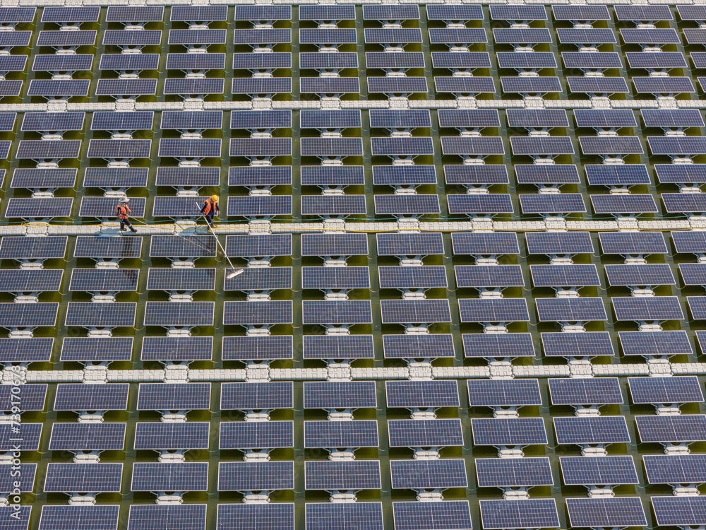 Fototapeta premium Worker Cleaning floating solar panels or solar cell Platform system on the lake with brush and water. Worker cleaning solar modules in a Solar Energy Power Plant